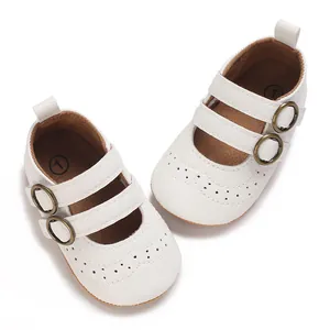 Close-up of white baby Mary Jane shoes with double straps and bronze buckles