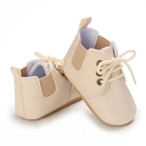 Primer plano de zapatos de bebé color crema con suela blanda y cordones.