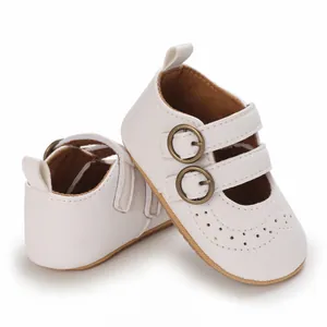 Macro view of white faux leather baby princess shoes featuring double bronze buckles