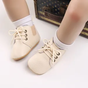 Detalle de zapatos para bebé color crema con suelas blandas y cordones blancos