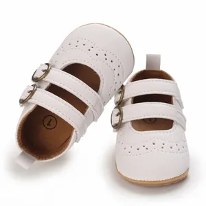 Detailed close-up of white baby Mary Jane shoes with brogue patterns and soft soles