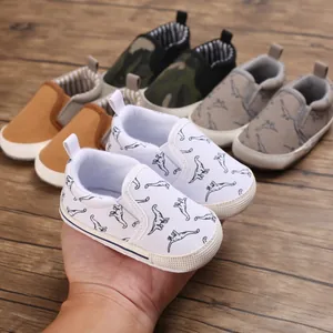 Close-up of baby walking shoes with white canvas and blue dinosaur print