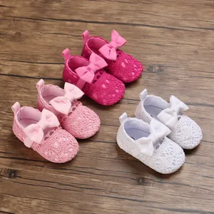 Detailaufnahme von gehäkelten Babyschuhen mit Schleifen in Rosa, Fuchsia und Weiß
