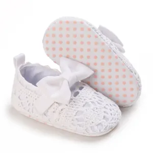 Nahaufnahme von weißen Baby-Prinzessinenschuhen aus Spitze mit weichen Punktsohlen.