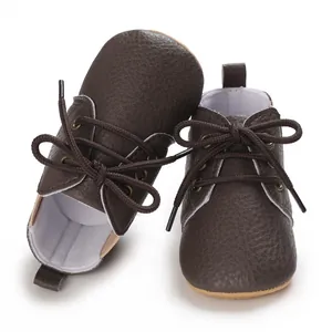 Detalle de zapatos de bebé en cuero marrón oscuro con suelas blandas y cordones