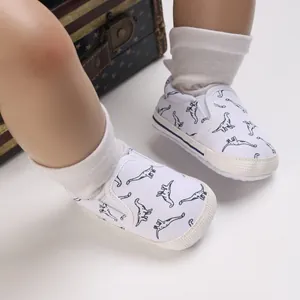 Detailopname van witte baby loopschoentjes met dinosaurusprint en zachte zool voor baby's