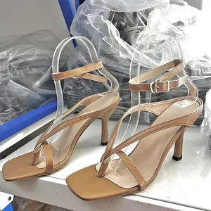 Camel thong high heel sandals with ankle strap and square toe in a factory setting