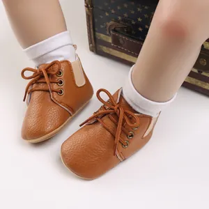 Detalle macro de zapatos de bebé de cuero sintético marrón con suelas blandas y cordones