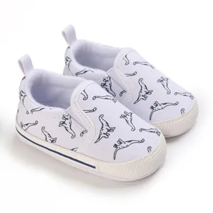 Detail van witte babyschoentjes met schattige dinosaurusprints en zachte zolen.