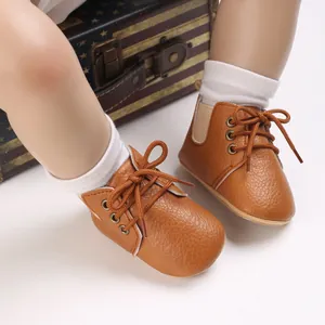 Primer plano de zapatos de bebé en imitación cuero marrón con suela blanda y cordones