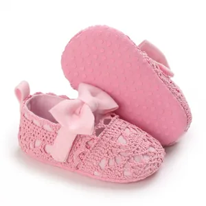 Detailansicht von rosa gehäkelten Babyschuhen mit Schleife und rutschfester Noppensohle