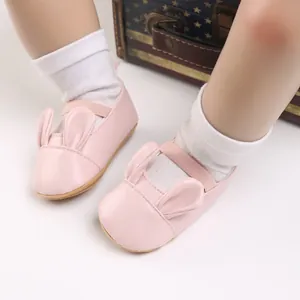 Close-up detail of pink baby girl walking shoes with cute cartoon rabbit ears and soft soles