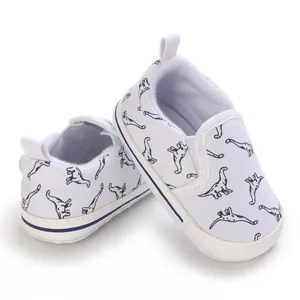 Detailweergave van witte baby canvas schoenen met blauwe dinosauriër patroon print.
