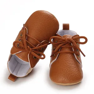 Primer plano de zapatos para bebé de cuero sintético marrón con suela blanda y cordones