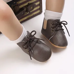 Vista detallada de zapatos de bebé en cuero sintético marrón con suelas blandas y cordones