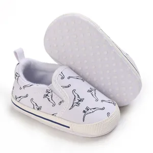 Detailopname van witte canvas baby loopschoentjes met dinosaurusprint en zachte zool