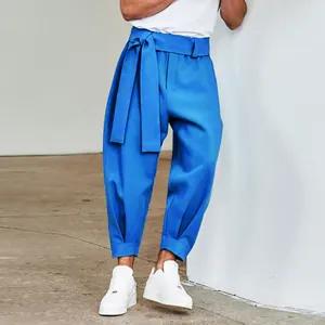 Detail view of stylish blue tapered trousers with a unique wide tie-waist belt