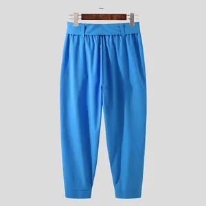 Full front view of bright blue men's cropped casual trousers on a wooden hanger.