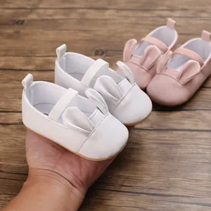 Close-up of baby girl walking shoes with cute bunny ear design in white and pink.