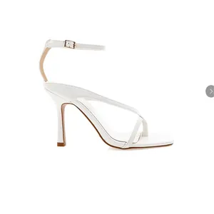 Side view of white stiletto sandals with thin cross straps and ankle buckle closure