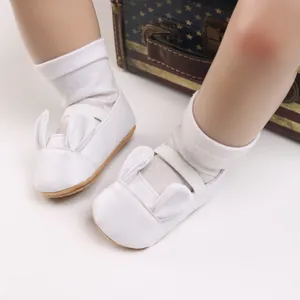 Close-up of white baby walking shoes with cute bunny ears and soft soles for infants