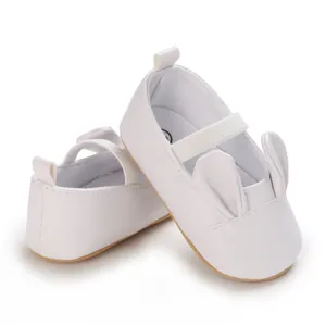 Close-up of white infant walking shoes with cute rabbit ear design and elastic strap
