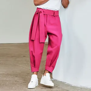 Detailed view of men's fuchsia cropped trousers featuring wide waist belt and tapered cuffs.