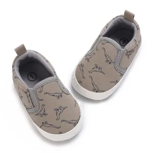 Detailed overhead view of infant walking shoes with blue dinosaur print on khaki canvas