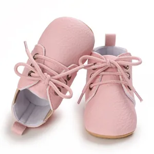 Detalle de zapatos para bebé en piel sintética rosa con suelas blandas y cordones