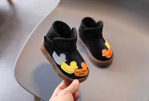 Primer plano de botas de nieve negras para niños con forro polar y parches de patitos.