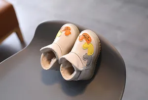 Vista detallada de botas de invierno beige para niños con parches de patos y forro cálido