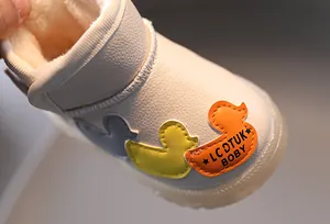 Primer plano de botas de nieve blancas para niños con parches de pato y forro cálido
