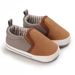 Gedetailleerde close-up van bruin-grijze canvas babyschoentjes met zachte witte zolen