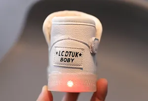 Detalle de bota de nieve blanca para niños con luz LED roja en la suela transparente