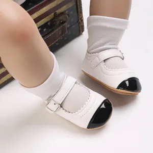Detailed view of white baby girl walking shoes featuring a black patent leather toe design