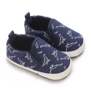 Close-up of navy blue baby slip-on walking shoes featuring white dinosaur patterns