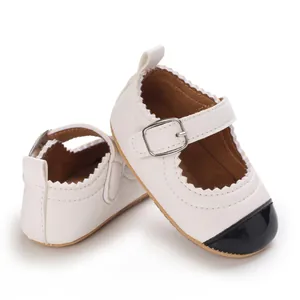 Detail view of white baby girl Mary Janes with black toe cap and silver buckle detail