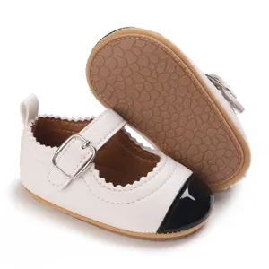 Detailed view of baby girl white Mary Jane shoes with black toe cap and rubber sole