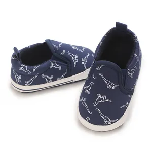 Detailed view of navy blue baby walking shoes with white dinosaur prints and soft white soles.