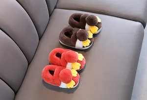 Dettaglio di graziose pantofole di peluche per bambini con design a pinguino rosso e marrone