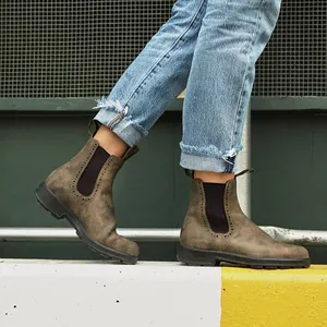 Primer plano de botas Chelsea marrones con detalles brogue llevadas con vaqueros en exteriores