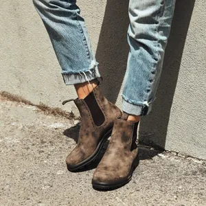 Primer plano de botines Chelsea de cuero marrón para mujer en un entorno urbano al aire libre
