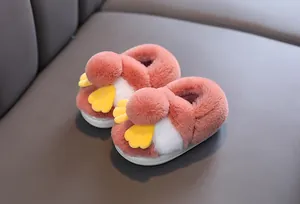 Primo piano di graziose pantofole in peluche rosa per bambini con design a uccellino