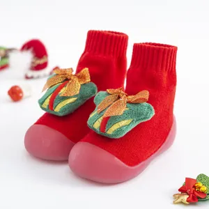 Chaussettes de marche de Noël rouges pour bébé avec décor de boîte cadeau verte.