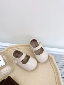 Top view detail of cream soft-sole baby Mary Jane leather shoes on a beige tray