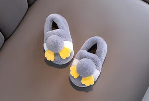 Primo piano macro di graziose pantofole di peluche grigie per bambini con piedi palmati gialli.
