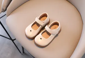 Close-up of off-white toddler girl heart Mary Janes with soft soles on a beige chair.