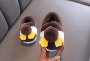 Vista dettagliata della morbida texture in peluche marrone delle pantofole a pinguino