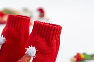 Vue macro de chaussettes de Noël rouges pour bébé avec pompons blancs et bords côtelés