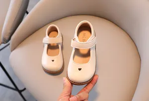 Close-up detail of cream-colored girl's Mary Jane shoe with heart-shaped cutout
